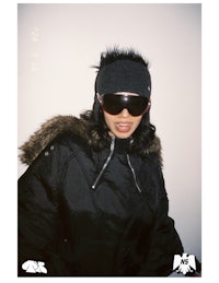 a woman in a black jacket and fur coat posing for a photo