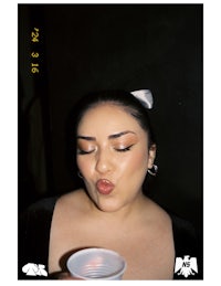 a woman is holding a cup and making a face